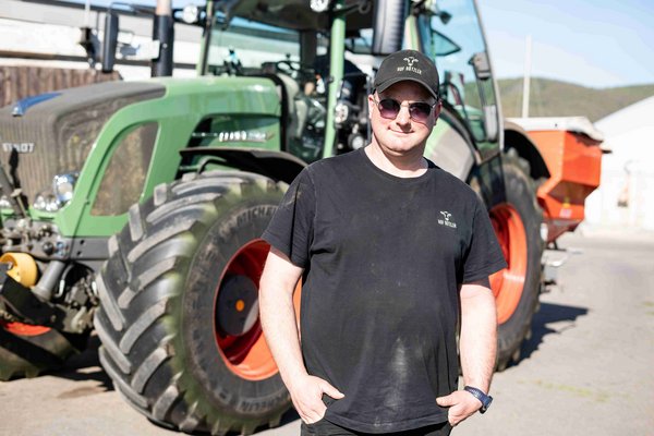 Milchkuhhalter Basti Bützler am Morgen des 1. Grasschnitts vor einem Traktor.