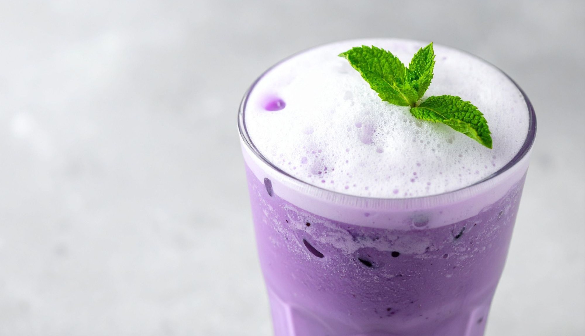 Erfrischende Ube Latte mit Eis und Minze